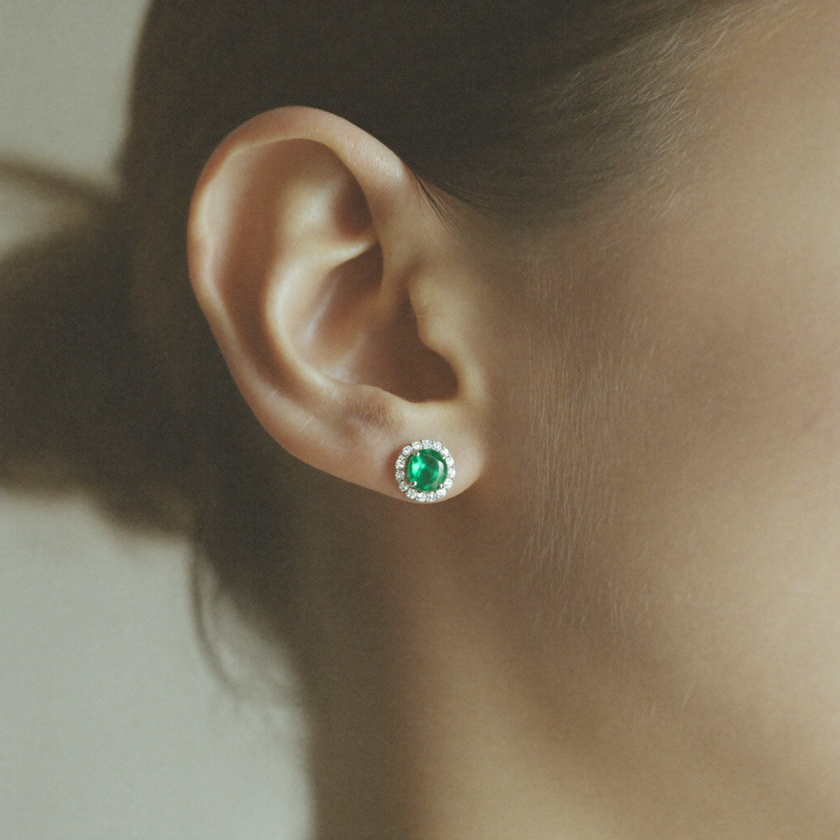 Model wearing the emerald halo stud earring, close-up editorial